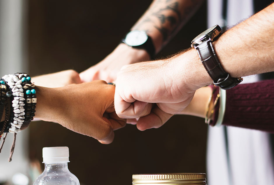Photograph of five businesspeople bumping fists